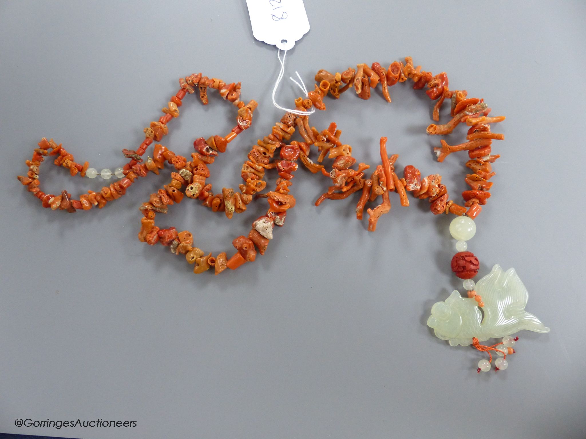 A jagged coral bead necklace, with jade pendant, carved as a fish, necklace approx. 88cm, fish length 66mm, gross weight 114 grams.